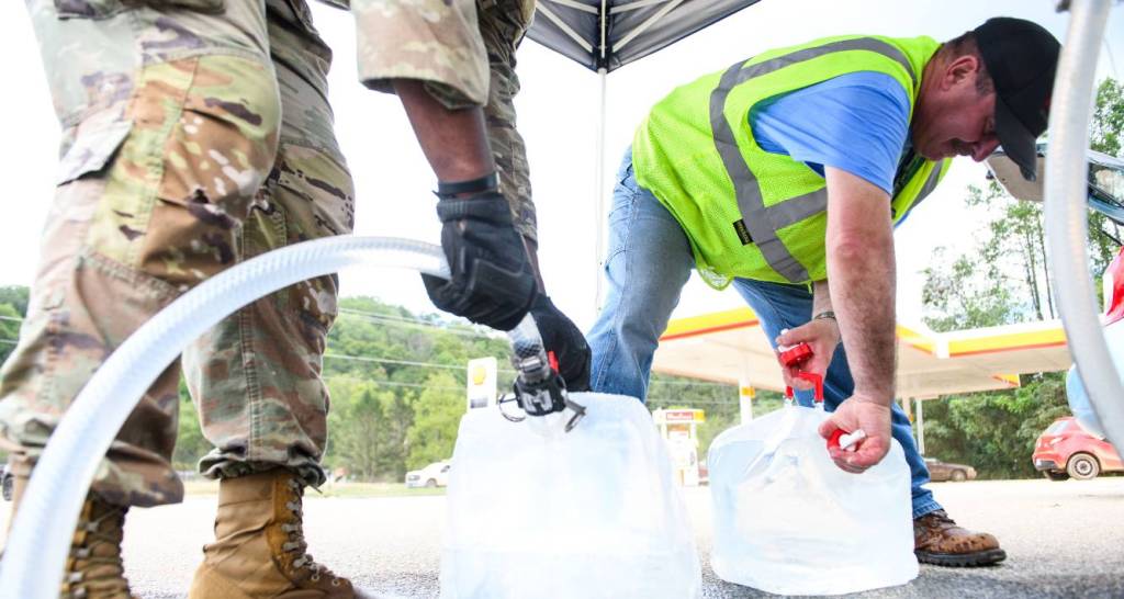 An Army National Guard member assists a resident with potable water in the aftermath of Hurricane Helene on Sept. 29 in Old Fort, N.C. Credit: Melissa Sue Gerrits/Getty Images