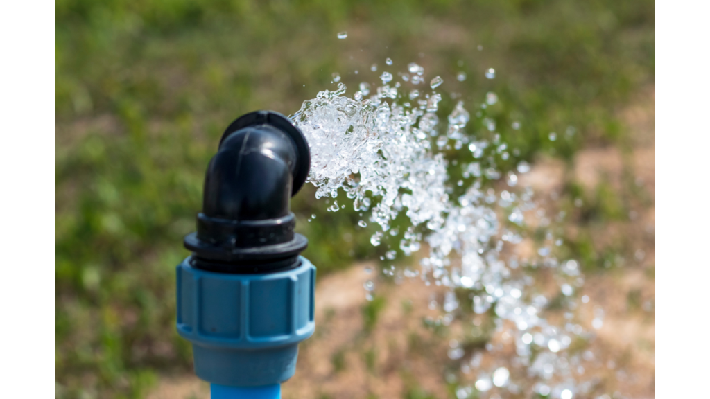 Water spraying out of spigot with green grass in background