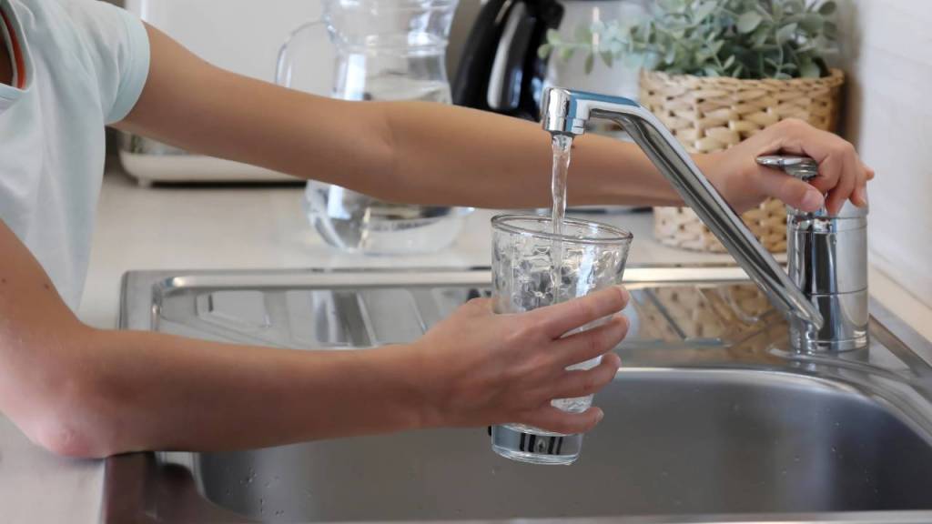 Kid getting fresh water to drink from kitchen sink in home.